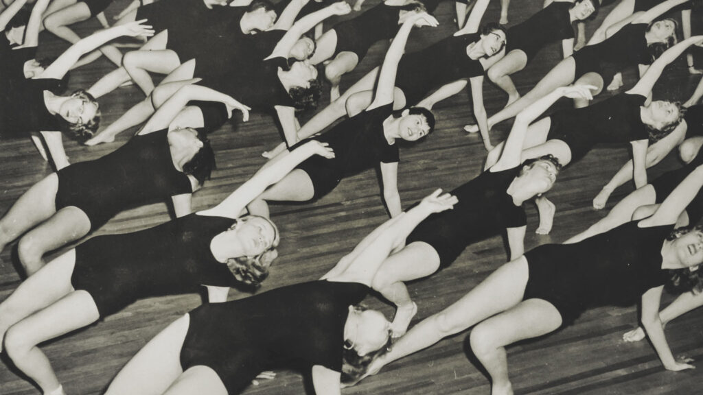 Students participate in a modern dance class in black leotards in 1966