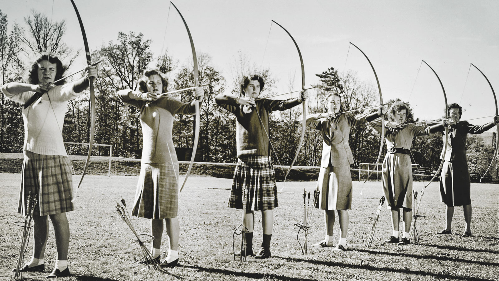 A line of women aim their bows and arrows during an archery class in 1947