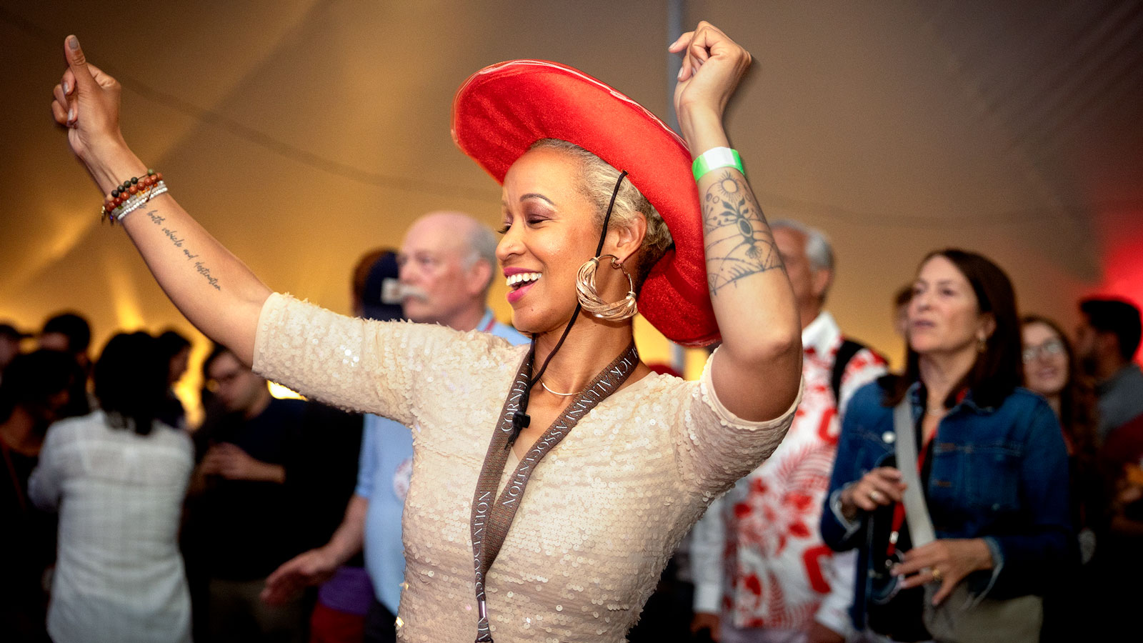 A Reunion attendee—wearing a red “Cornellians” cowboy hat—dances in an Arts Quad tent during Reunion 2024