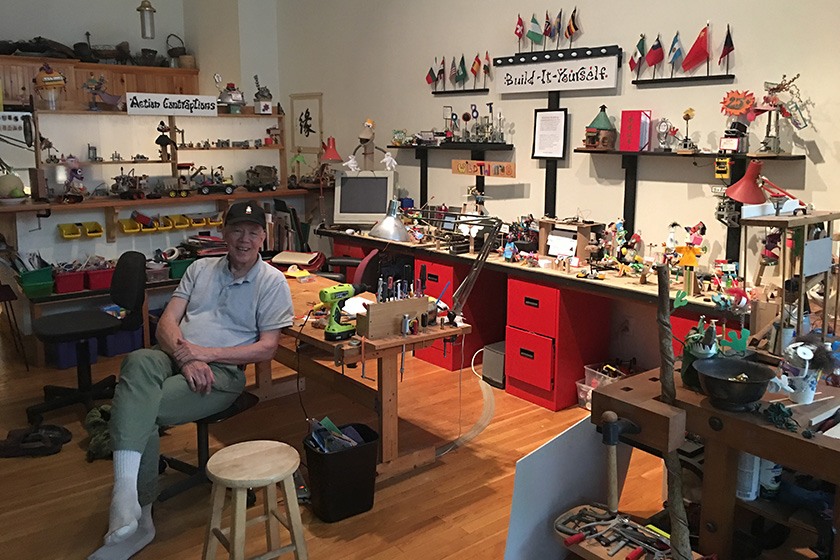 John Galinato '66 sits in the Build It Yourself workshop surrounded by tools, puppets, and contraptions.