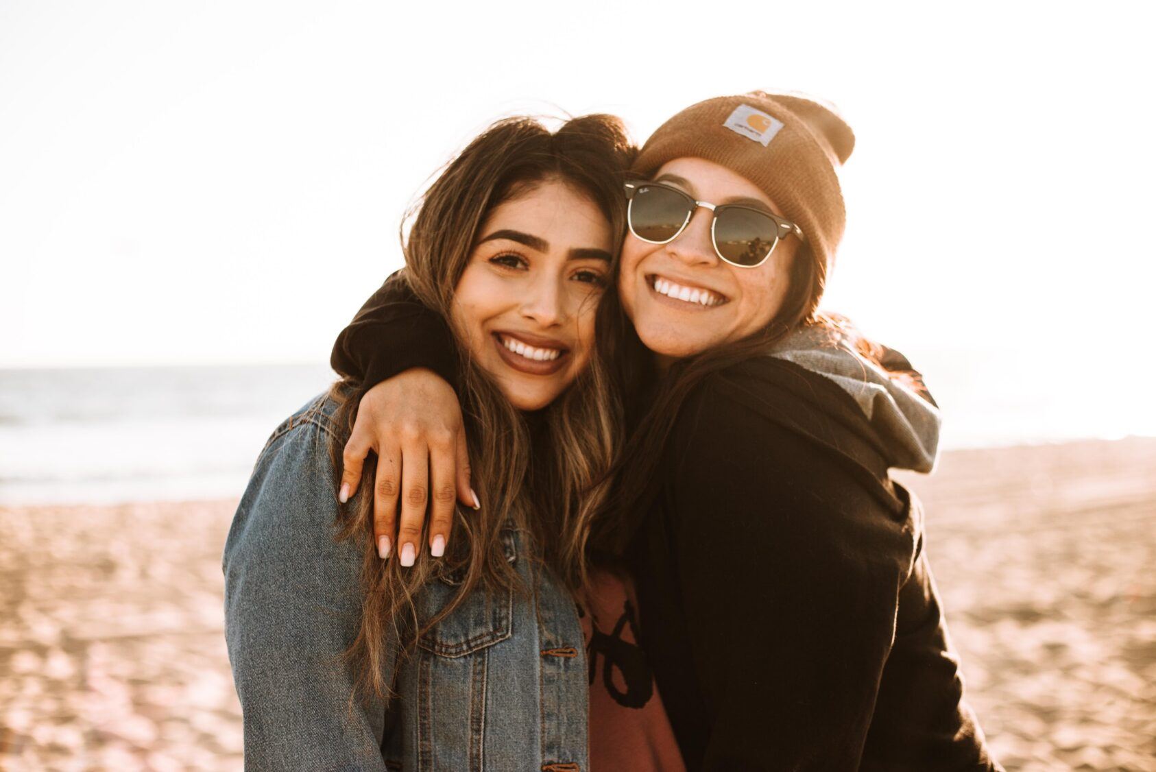 two women at the beach hugging each other